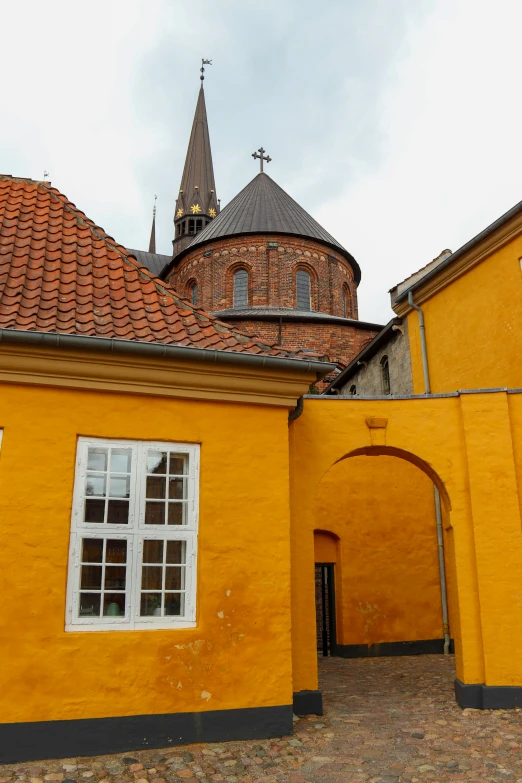 a yellow building with arched windows in front of a brown brick church