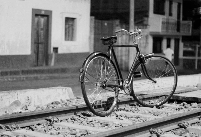 black and white po of bicycle resting on train tracks