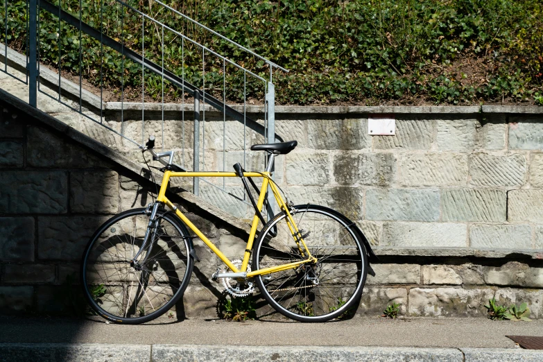 a yellow bike parked against a stone wall