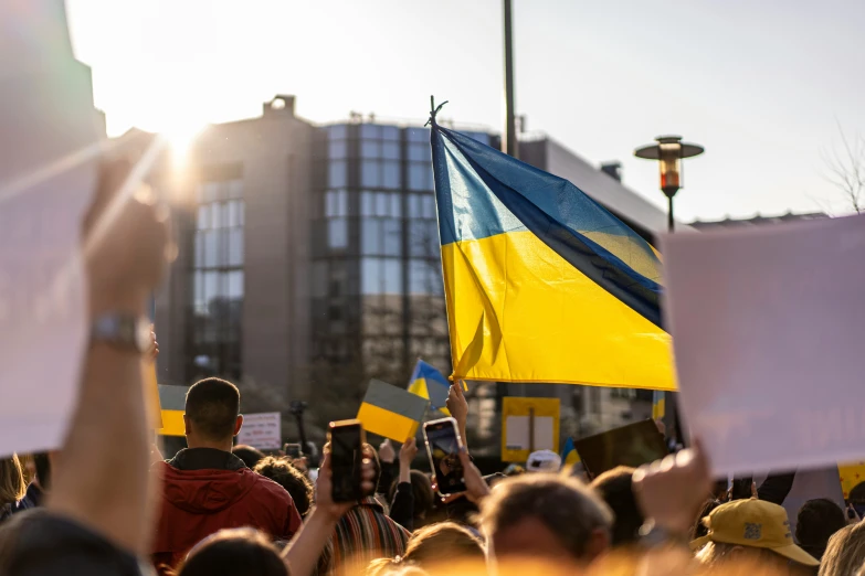 a group of people holding signs with ukraine and ukraine flags