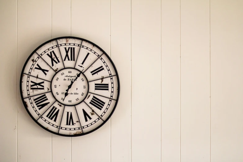 a large clock mounted to the side of a white wall