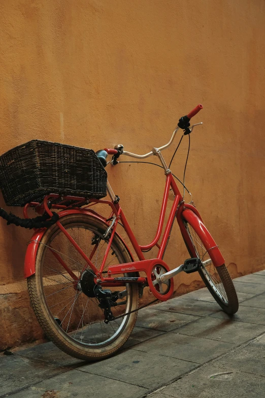 red bicycle with basket parked by the wall