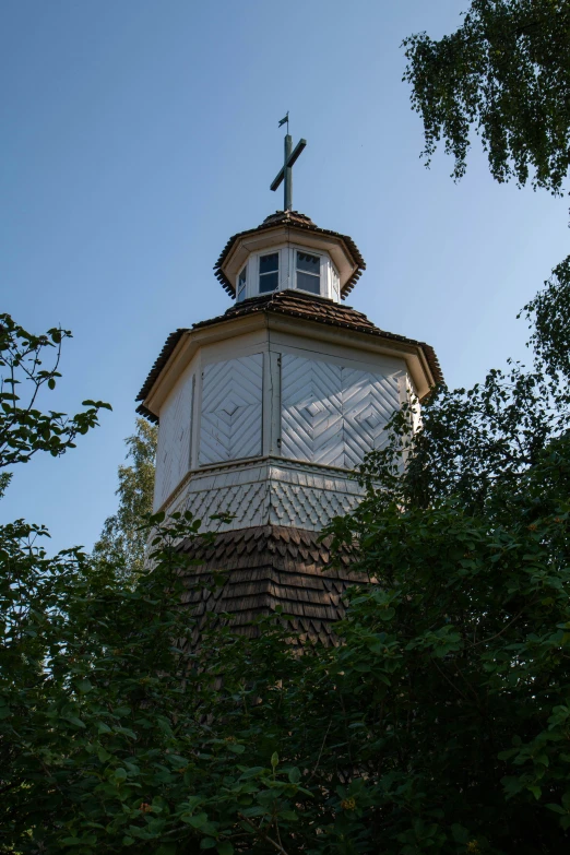 a clock tower with a weather vein is seen from the bottom