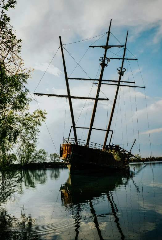 a sailboat sits anchored along the bank of a calm river