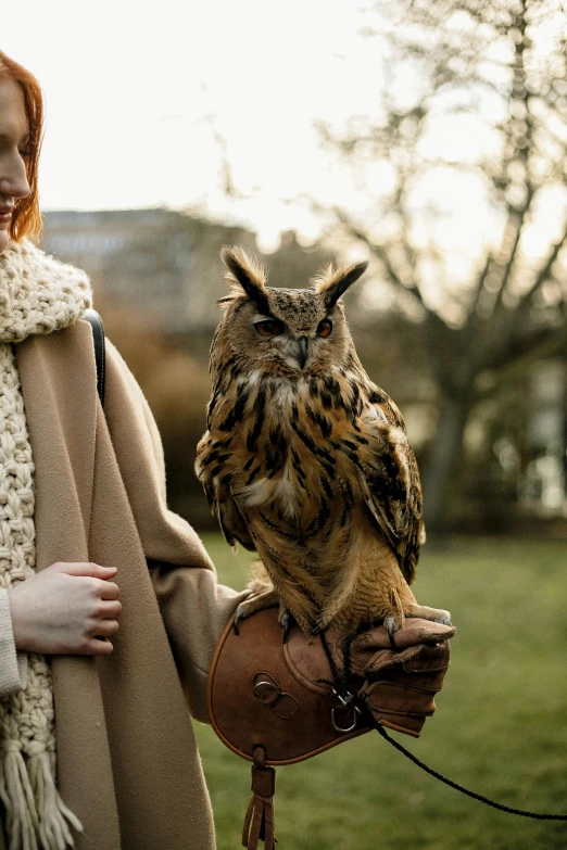 the woman is holding an owl and posing for the camera