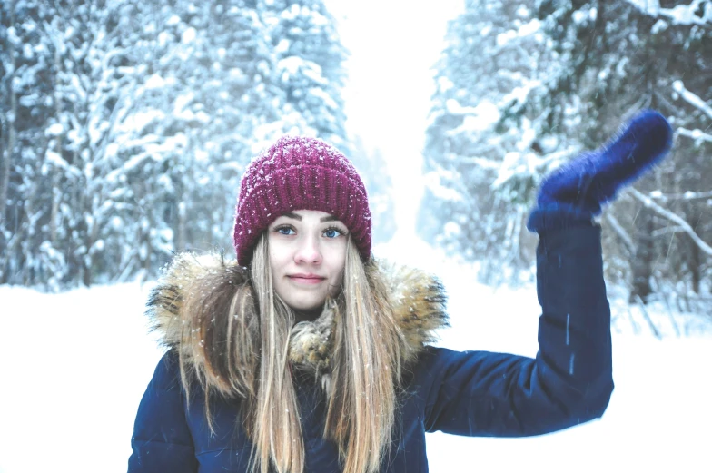 a woman standing on a snow covered slope holding up a frisbee