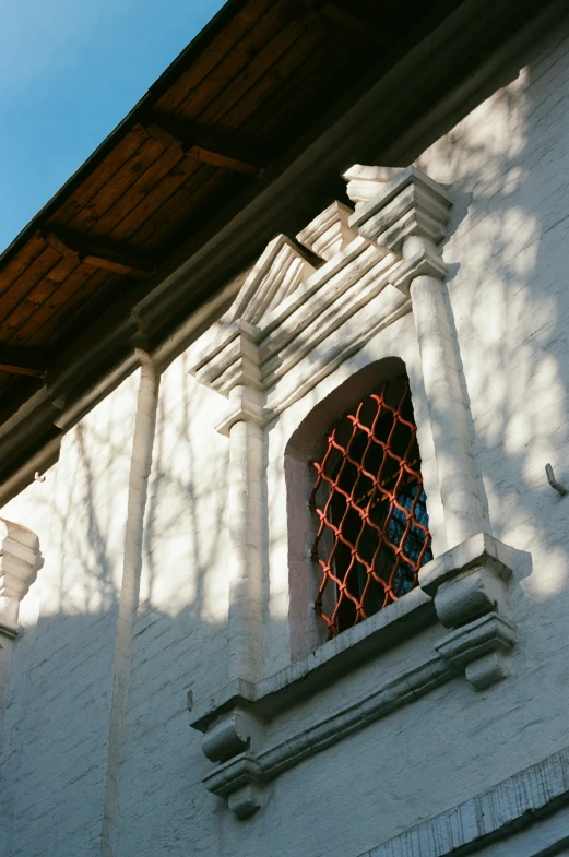 a view of the side of a white building with a red net window