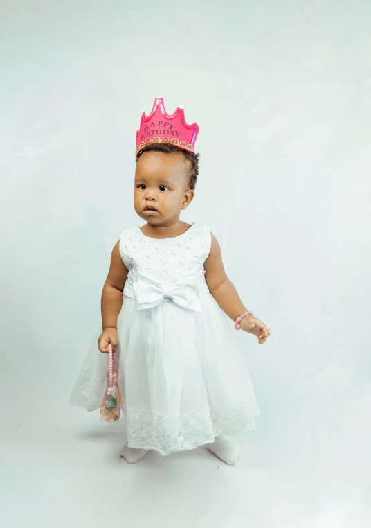 a small toddler girl dressed in white with a princess tiara