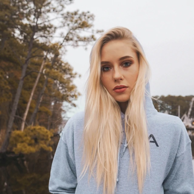 a blonde girl in a hoodie is standing