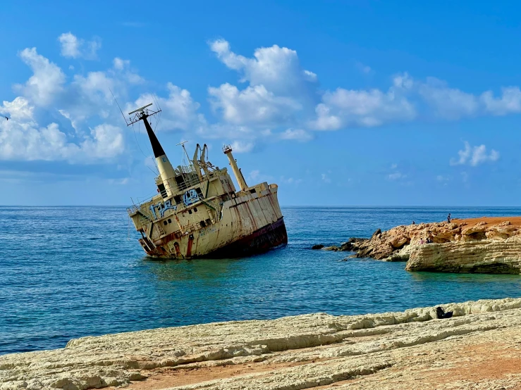 a ship sitting in the water with people walking by