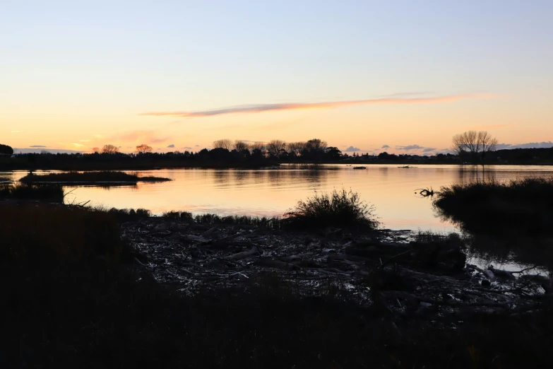 a body of water at dusk with a few boats out of focus