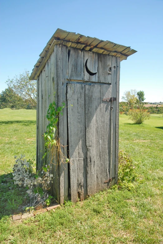 a wooden outhouse with a moon and stars on the side