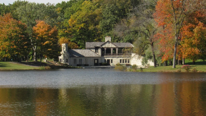 a small white house next to a pond in the middle of trees