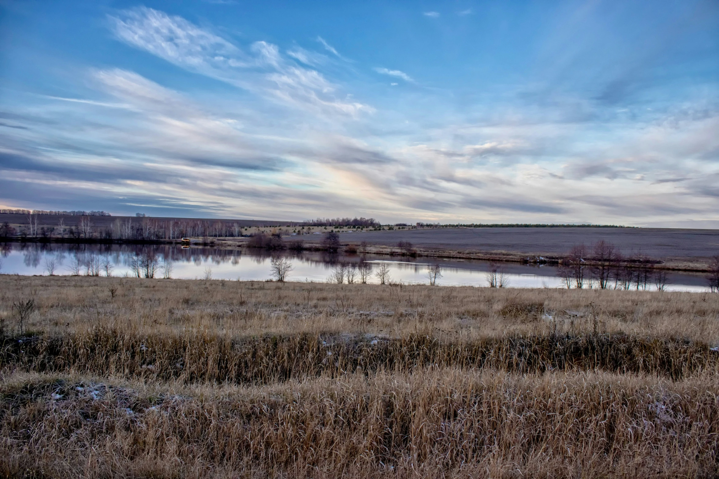 the fields are brown and dry with grass in front of it