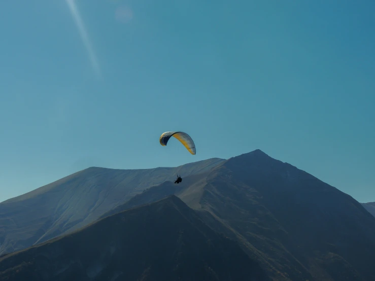 someone parasailing in front of a mountain