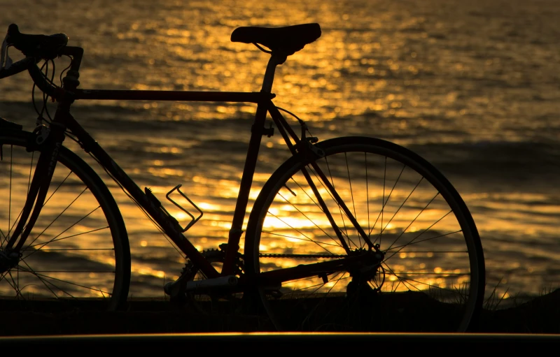 a bike is shown against a sunset over the ocean