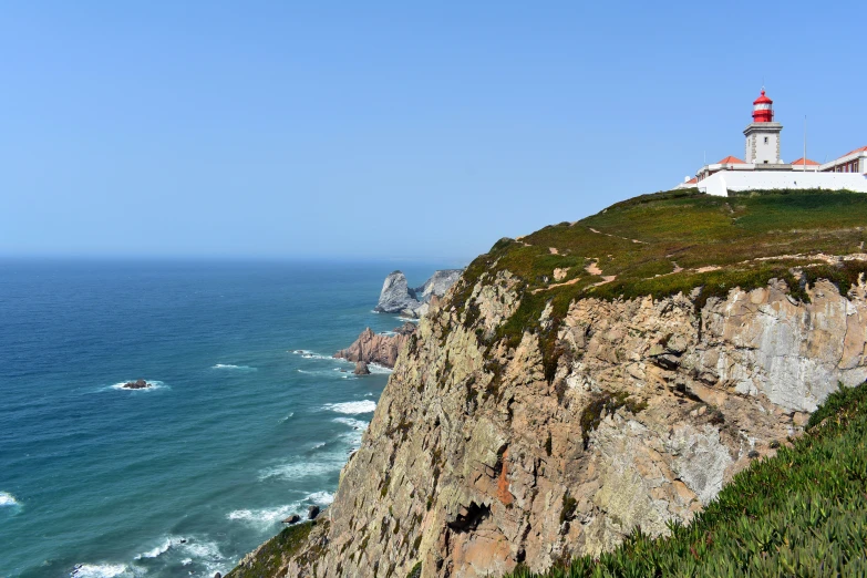 the view from a cliff overlooking a lighthouse and sea