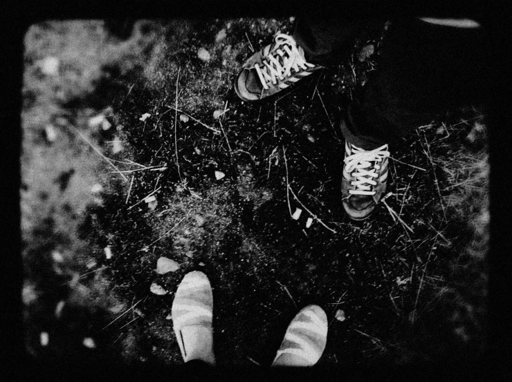 legs and shoes are seen from above in this black and white pograph