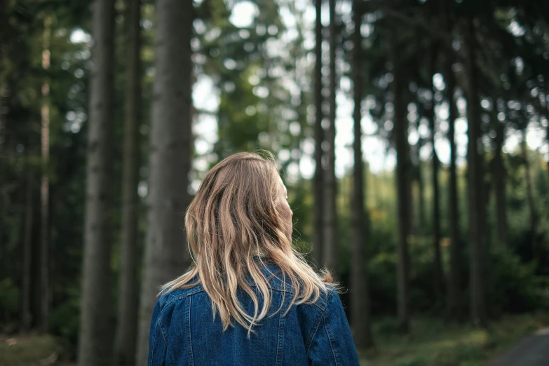 a woman walking down the street with trees behind her