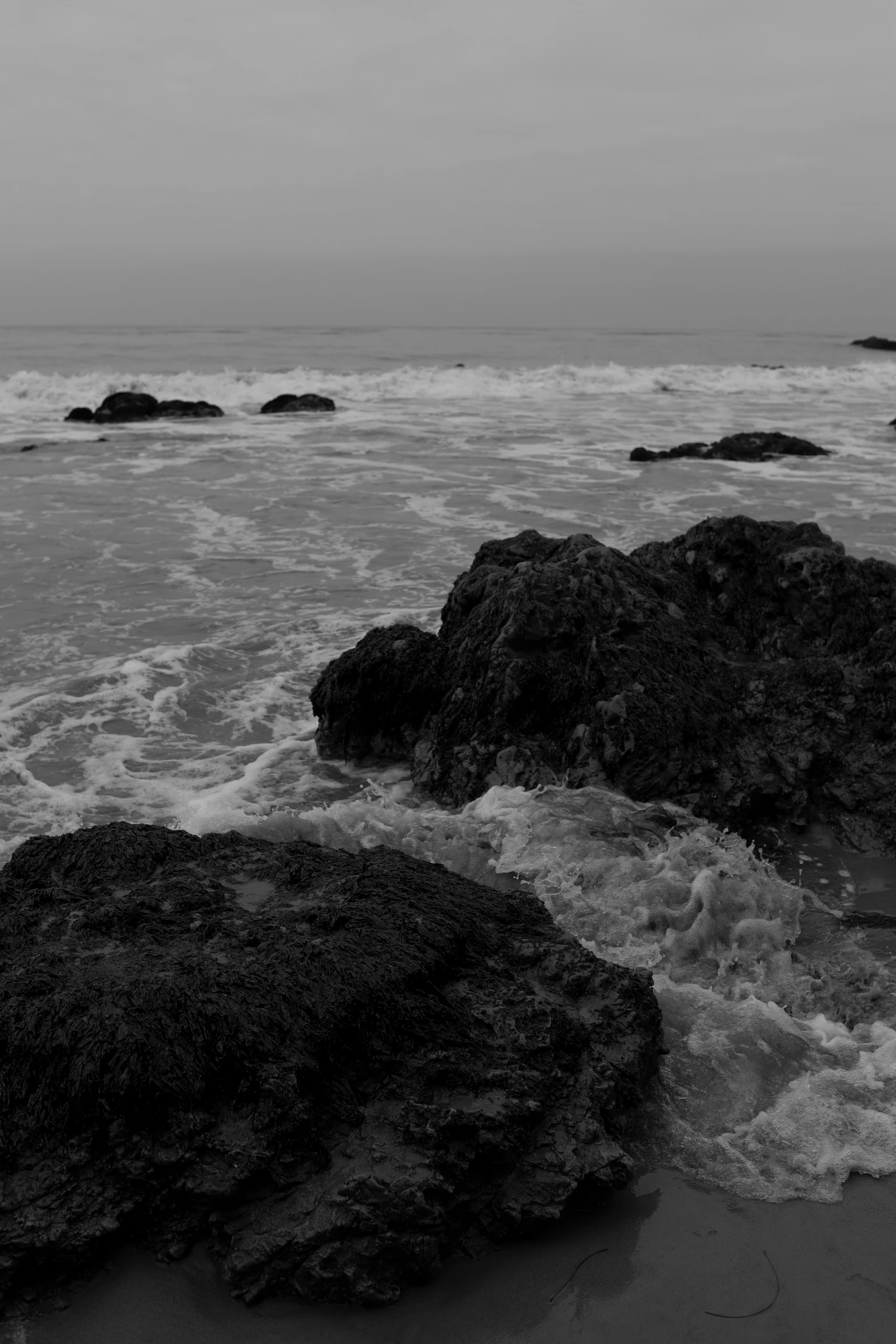 a black and white po of rocks on the beach