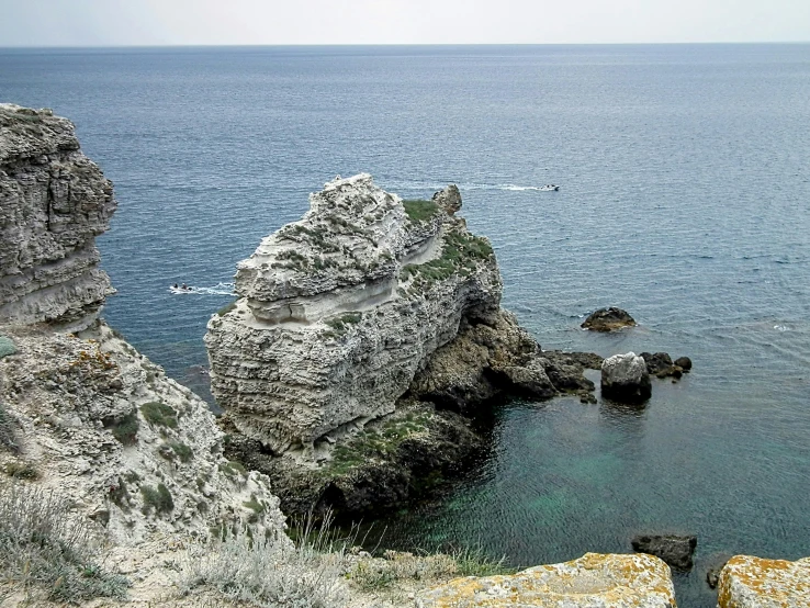 a lone boat out in the sea between two rocks