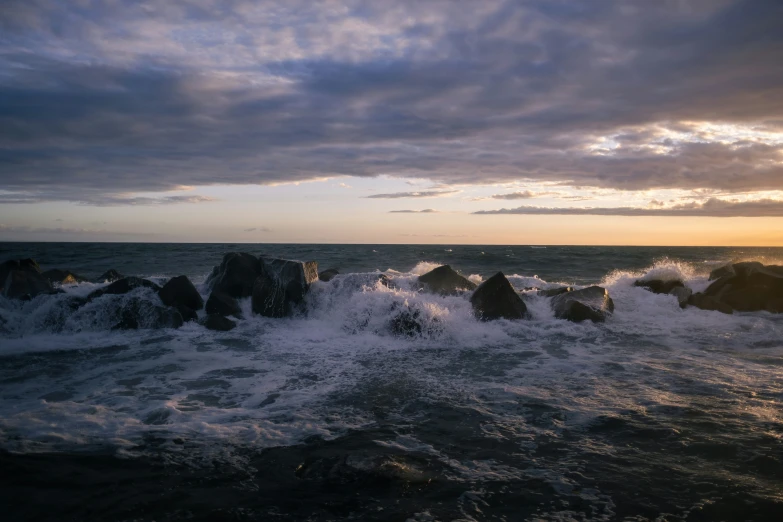 waves coming in on rocks as the sun goes down