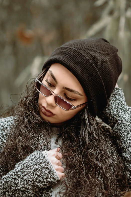 a woman with long, curly hair wearing sunglasses and a hat