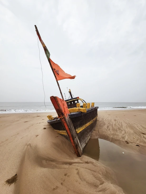 a boat that has a flag stuck in the sand