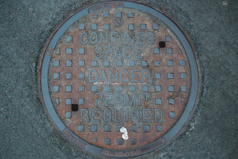 a manhole cover in the street with words and numbers written on it