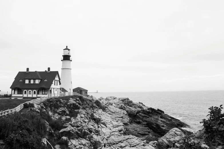 black and white pograph of a light house on a rocky cliff