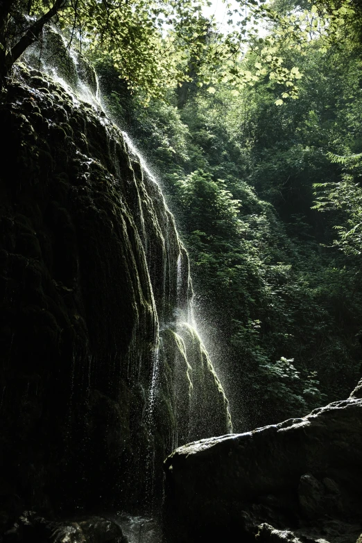 the man stands at the bottom of a waterfall