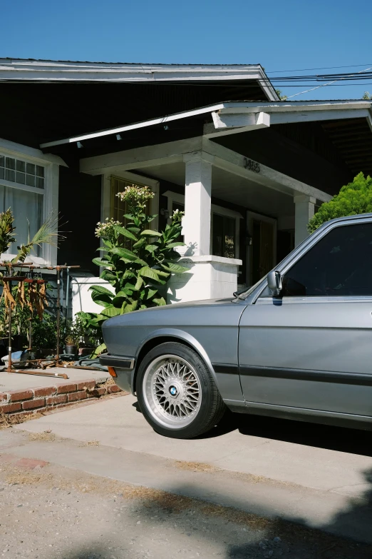 an bmw is parked outside of a house with its rear door open