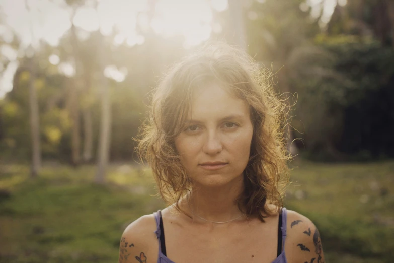 a woman with tattoos standing in a forest