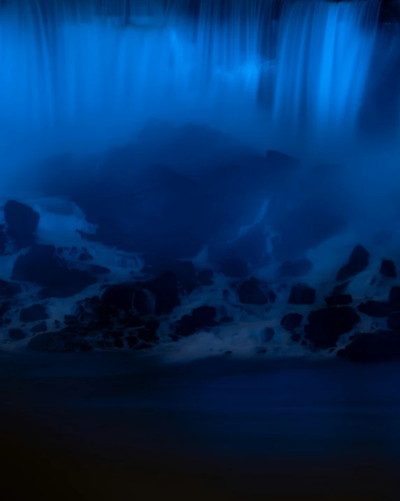 a waterfall that is surrounded by dark blue lights