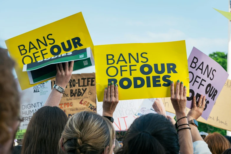 a group of people holding signs that read bans off our bodies