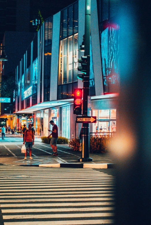 people crossing the street at night in a city