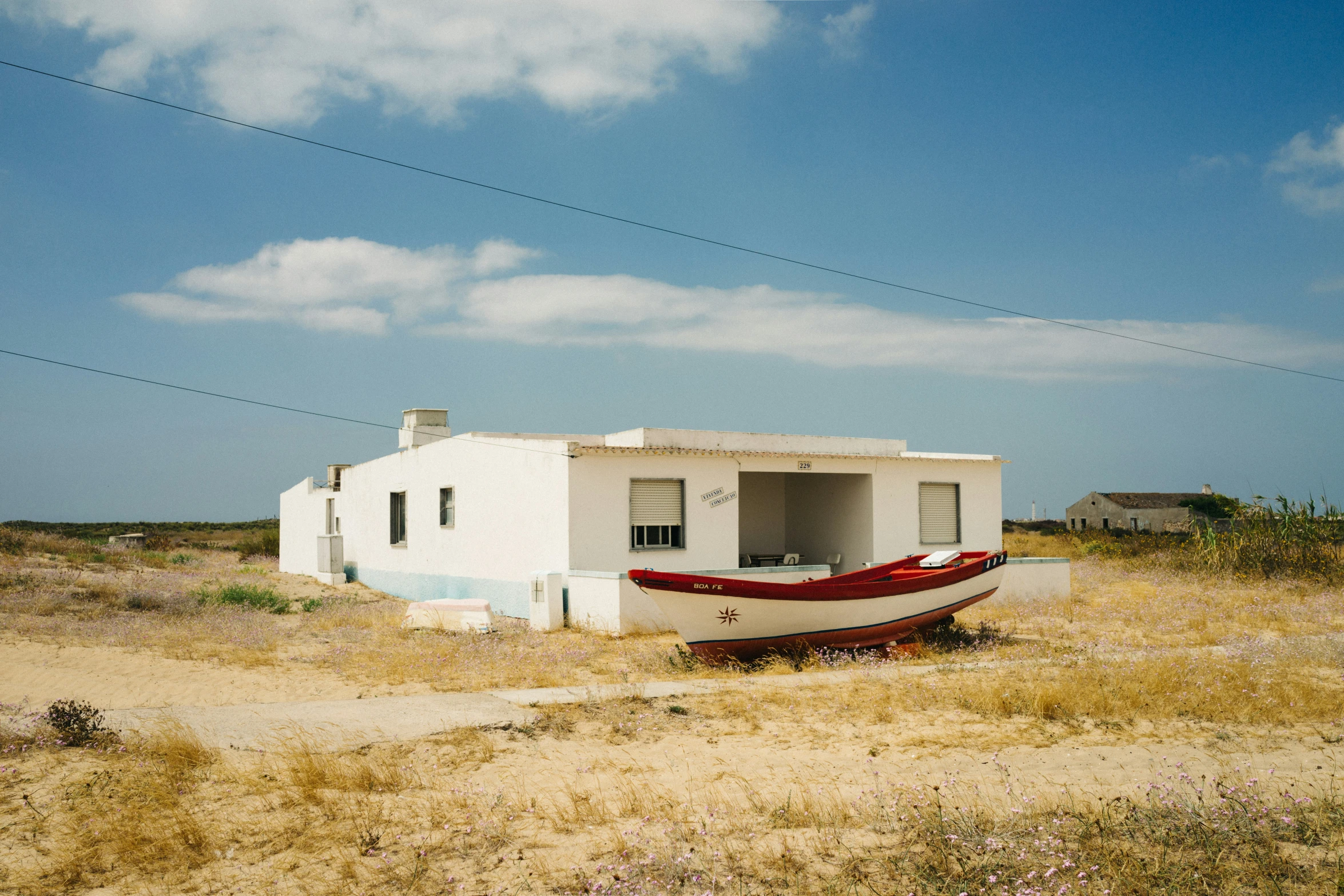 a white building with a red boat near by