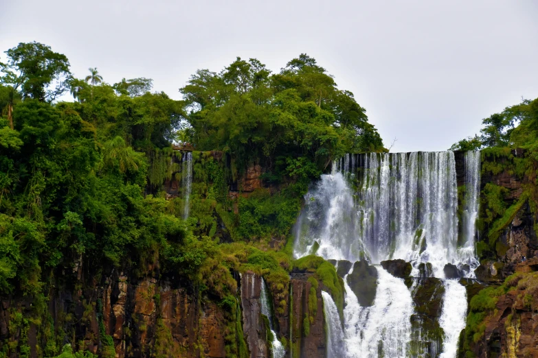 three tall waterfalls with lush vegetation at the bottom