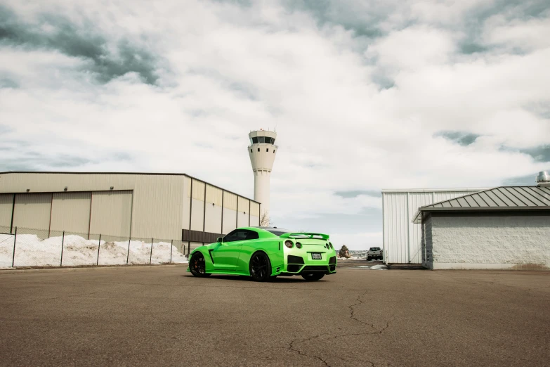 a green car is parked in front of an airport control tower