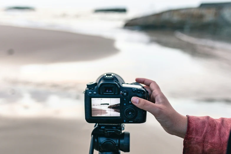 a person takes pictures with a camera with the ocean in the background