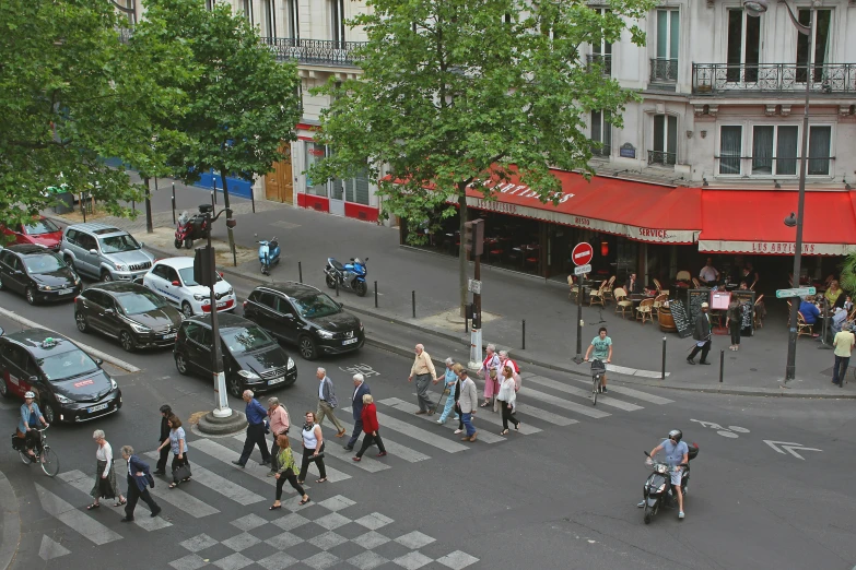 many people are crossing a busy street in front of buildings