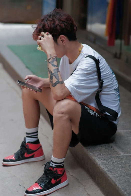 a man sits on the side of the street with his cell phone