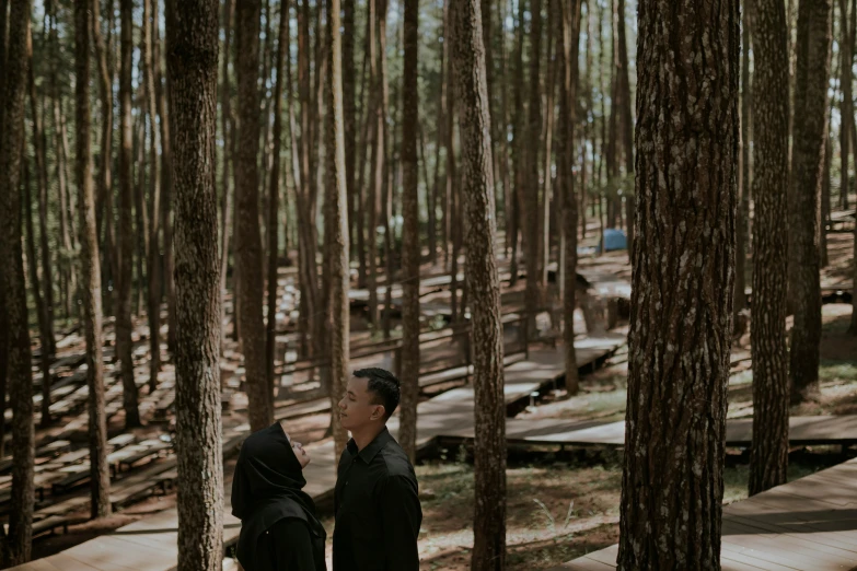 man and woman standing in an area with trees