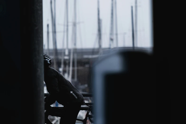 a man sitting on a bench next to a pole with some bikes in the background