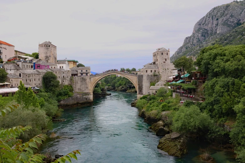 a city is seen near the river and bridge