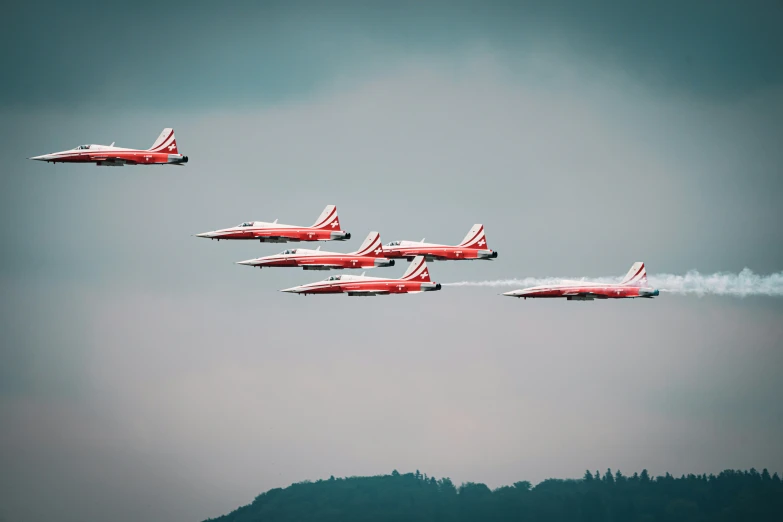 several airplanes fly with exhaust coming from the tail