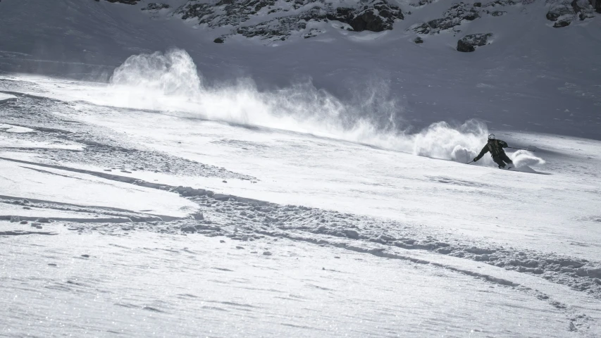 the man snowboarding is coming down the hill with lots of powder