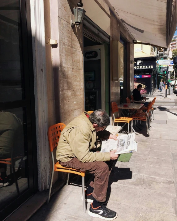 a man sitting on a bench reading a paper