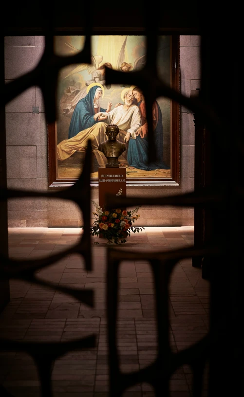 a cross in front of a painting next to a fence