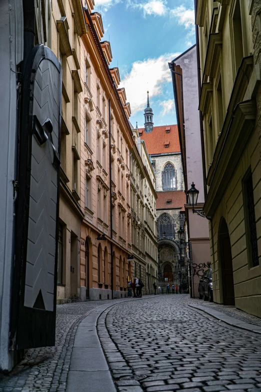 an old cobbled stone street leads to a building with tall windows